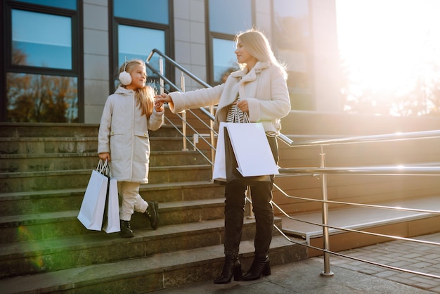 Mãe jovem e menina com sacos de compras depois de fazer compras Spring Style Consumerism