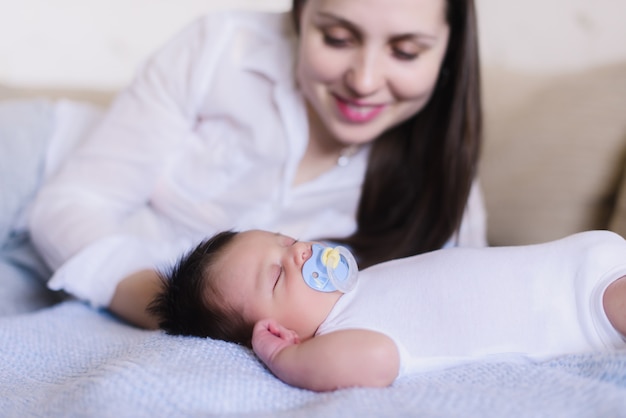 Mãe jovem feliz perto de bebê dormindo