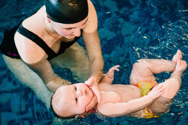 Mãe jovem, menina feliz na piscina