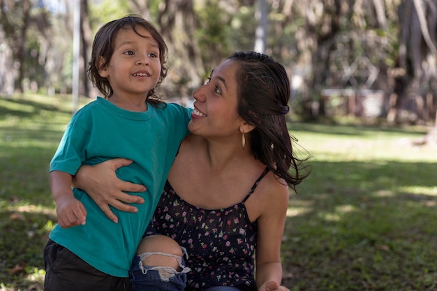 Mãe latina americana abraça alegremente com seu filho de 3 anos no parque conceito de família e dia da mãe