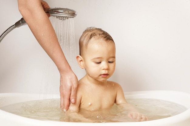 Mãe lavando e dando banho em seu filho pequeno