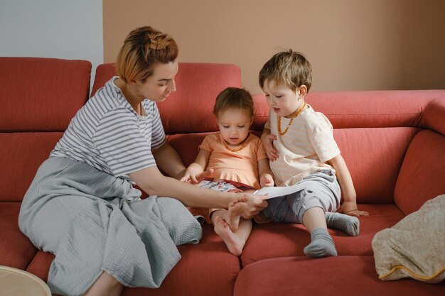 Mãe lendo livro com dois filhos no sofá