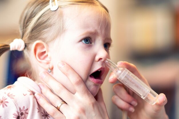 Mãe limpando o nariz do bebê com aspiração nasal