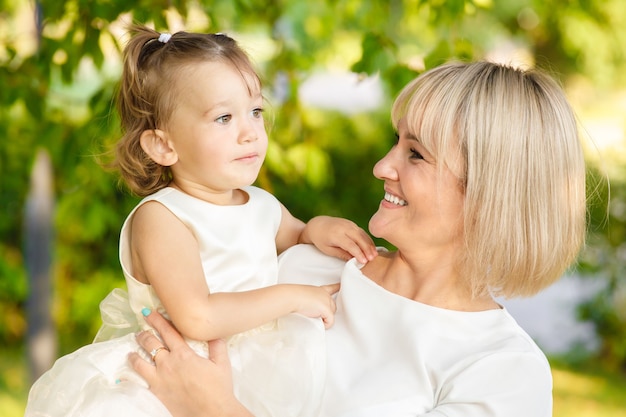 Mãe loira com filha no parque no verão em tempo ensolarado