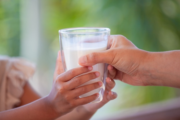 Mãe mão dando copo de leite para seu filho com carinho e amor