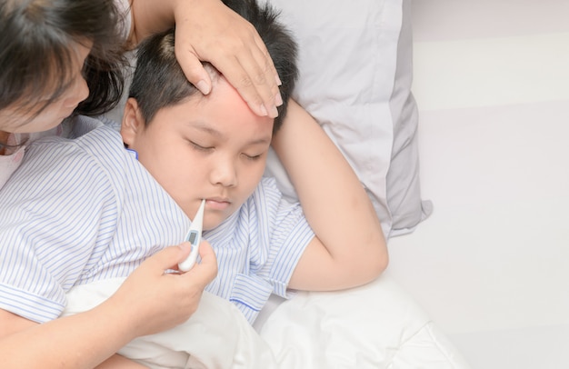 Mãe, medindo a temperatura do garoto doente.