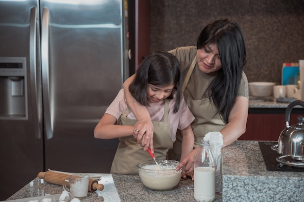 Mãe mexicana ensinando filha a cozinhar na cozinha