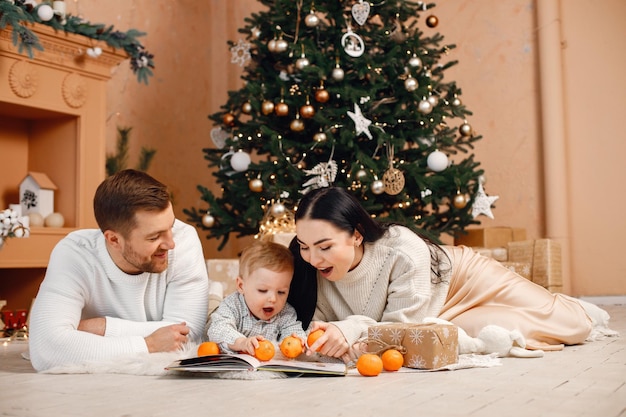 Mãe morena pai e filho sentado perto da árvore de Natal