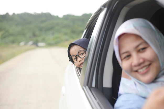 Mãe muçulmana asiática e filha feliz sorrindo em viagem de carro férias imagem de foco seletivo