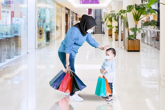 Mãe muçulmana e filho usando máscara facial no shopping