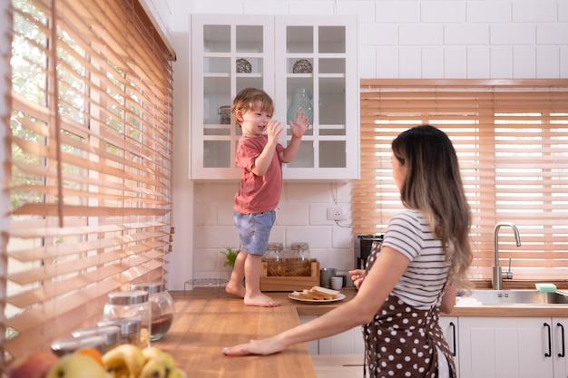 Mãe na cozinha da casa com uma criança pequena Brincar e se divertir cozinhando o jantar juntos