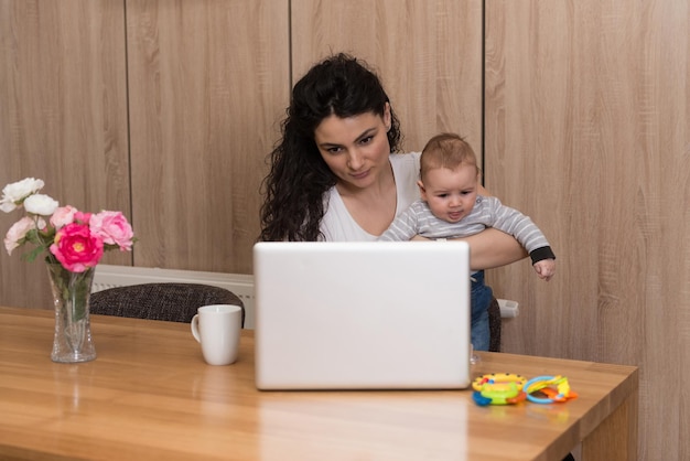 Mãe na sala de estar com bebê usando laptop