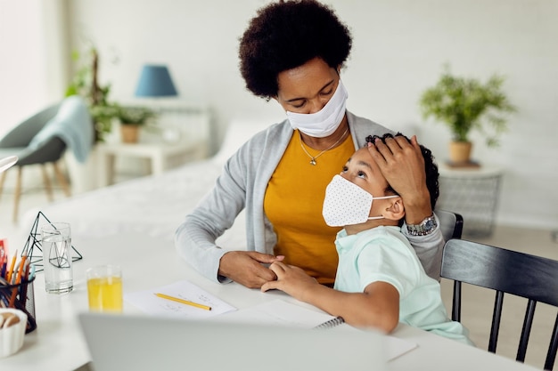 Mãe negra carinhosa consolando seu filho enquanto estudava em casa durante a pandemia de coronavírus