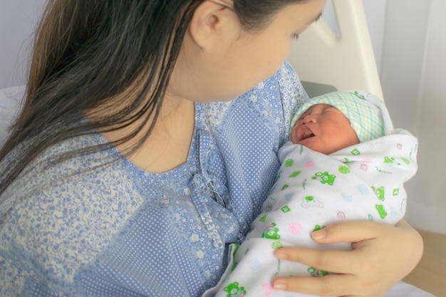 Foto mãe olha para seu bebê recém-nascido na cama imediatamente após um parto. foto do conceito de mulher grávida, recém-nascido, bebê, gravidez.
