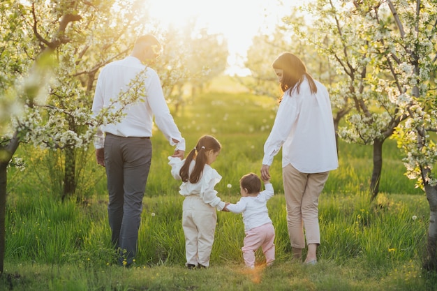 Mãe, pai e duas filhas caminham na natureza