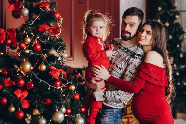 Mãe pai e filha no fundo de uma árvore de Natal