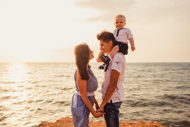 Mãe, pai e filho. a família passeia pela praia pedregosa à beira-mar.