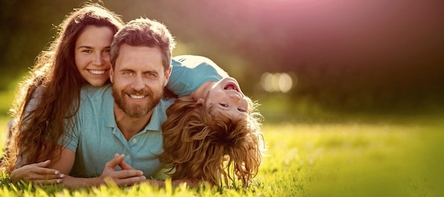 Mãe, pai e filho amam relaxar juntos Banner do dia da família com espaço de cópia Banner da família feliz Deitada na grama Jovem mãe e pai com filho filho no parque descansando juntos na grama verde