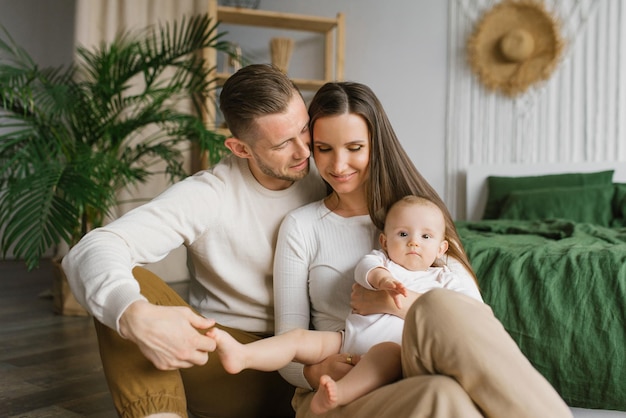 Mãe, pai e filho bebê de seis meses em seus braços passam um tempo juntos em sua casa aconchegante