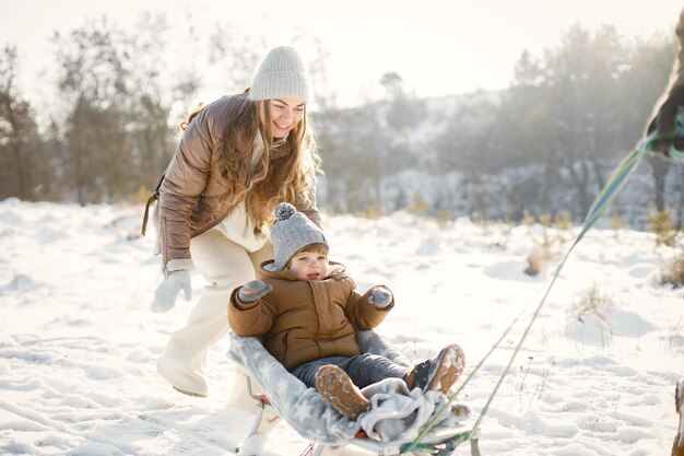 Mãe pai e filho pequeno passando tempo juntos no dia de inverno em um trenó