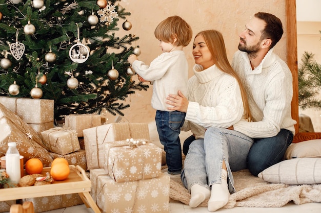 Mãe pai e filho sentado perto da árvore de natal em casa