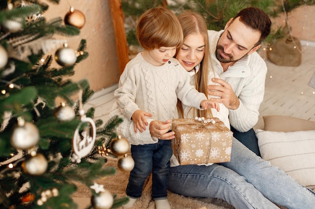 Mãe pai e filho sentado perto da árvore de natal em casa