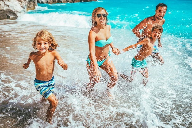 Mãe pai e filhos estão correndo na praia de verão.