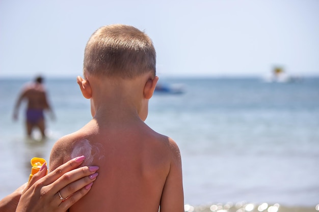 Mãe passa creme nas costas do filho Cuidando da pele do bebê Protetores solares na viagem