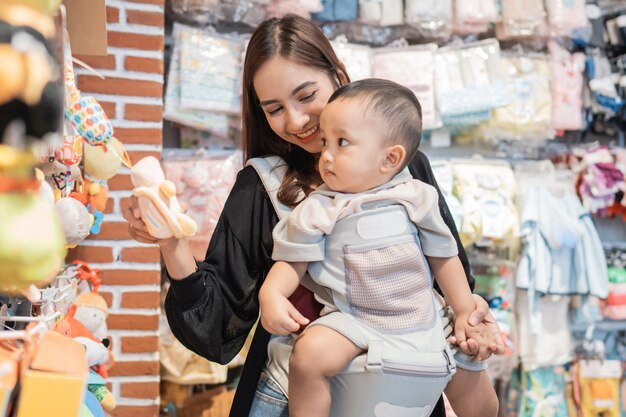 Mãe pegando algum produto na loja de bebês enquanto carregava seu filho