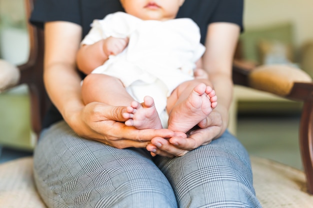 Mãe que guarda os pés recém-nascidos do bebê em suas mãos da mamã.