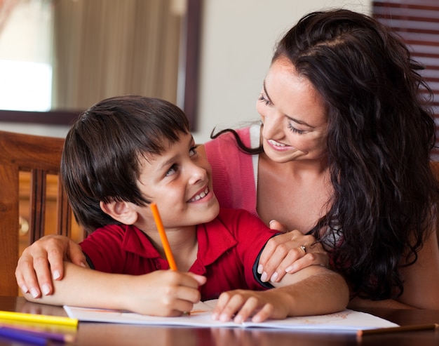 Mãe radiante que ajuda seu filho a fazer a lição de casa
