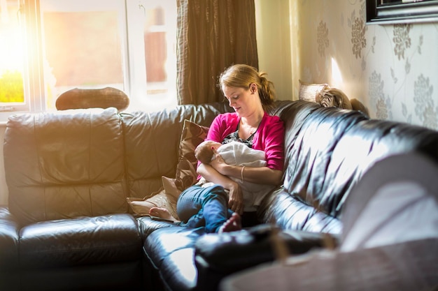 Mãe relaxante com bebê dormindo no sofá