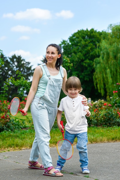 Mãe rindo rola nas costas do filho pequeno no parque