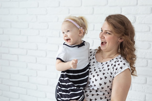 Mãe segura seu filho com aparelhos auditivos e implantes cocleares na parede de tijolos brancos com espaço de cópia