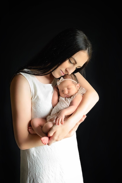 Mãe segura um bebê recém-nascido em seus braços em um fundo preto Dia das Mães