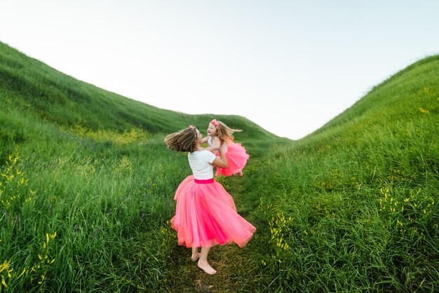 Foto mãe segura vomita e gira a filha nas mãos na natureza nas férias de verão mãe e menina brincando no parque conceito de família amigável fechar