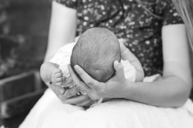 Foto mãe segurando a cabeça de seu filho recém-nascido nas mãos o bebê nas mãos da mãe mãe amorosa segurando a mão do bebê recém-nascido dormindo fofo