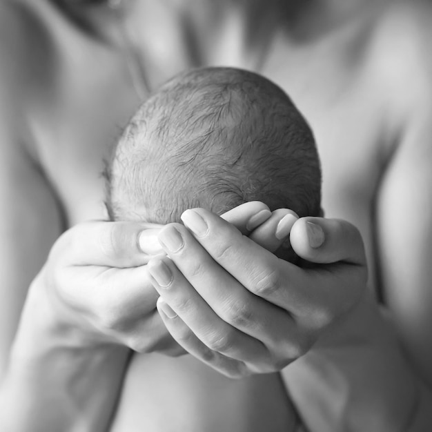 Mãe segurando a cabeça de seu filho recém-nascido nas mãos O bebê nas mãos da mãe Mãe amorosa segurando a mão do bebê recém-nascido dormindo fofo