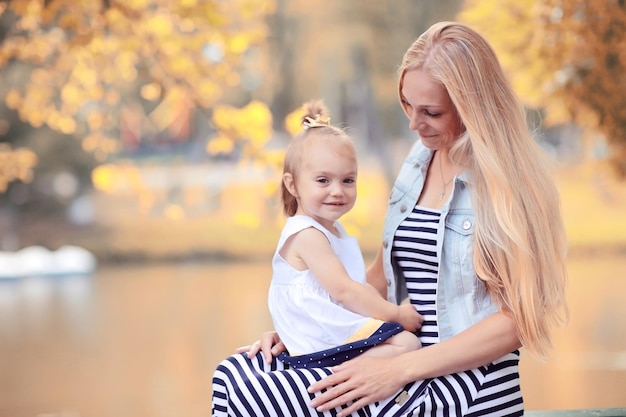 Mãe segurando a filha nos braços fotos de outono no parque amarelo