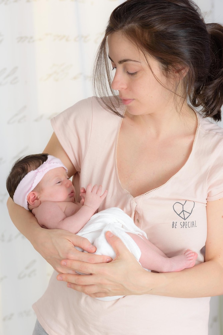 Foto mãe segurando a filha recém-nascida enquanto está em casa