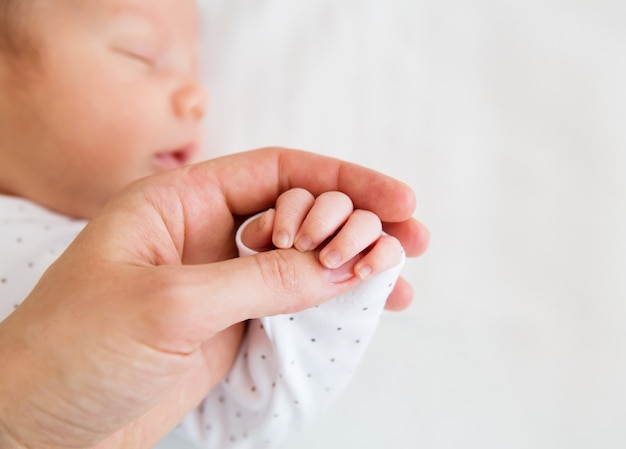 Mãe segurando a mãozinha de um bebê recém-nascido