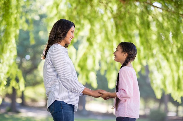 Mãe, segurando as mãos de sua filha no parque