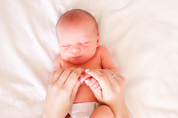 Mãe segurando as mãos do bebê adormecido