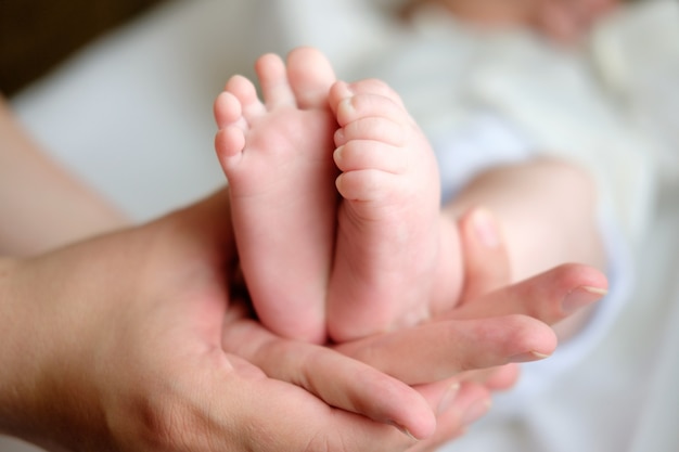 Mãe, segurando as pernas do bebê