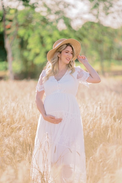 Mãe segurando chapéu e mão na barriga de grávida