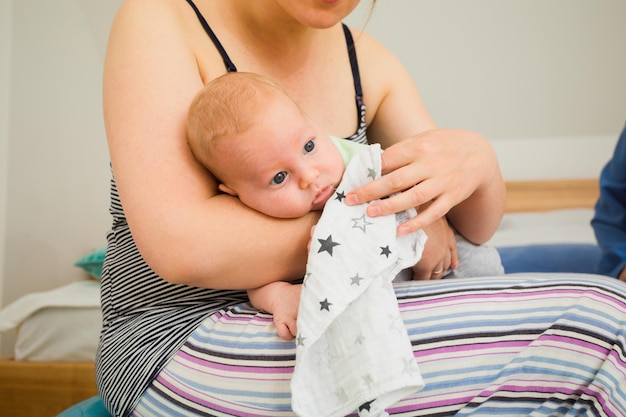 Mãe segurando e balançando o bebê sentado na fitball