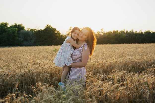 Mãe segurando em seus braços filho bonito em um campo de trigo