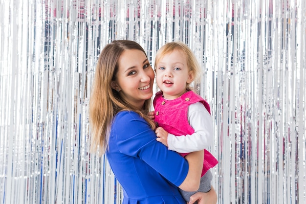 Mãe segurando filha bebê na parede brilhante