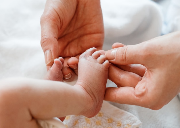 Mãe, segurando os dedos da criança nas mãos