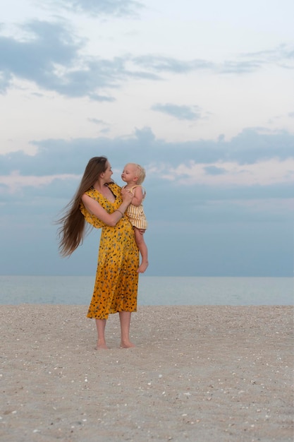 Mãe segurando seu bebê à beira-mar quadro vertical